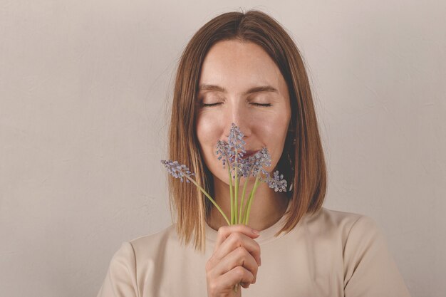 Linda mulher caucasiana com flores de muscari nas mãos