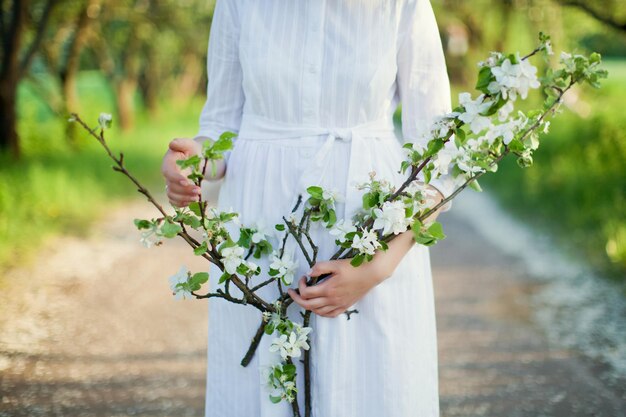 Linda mulher caucasiana de vestido branco caminha no jardim de flores da primavera