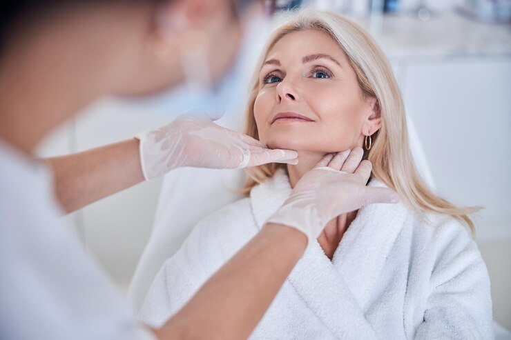 Linda mulher caucasiana loira em roupão branco sentado no sofá de beleza enquanto olha para o doc...
