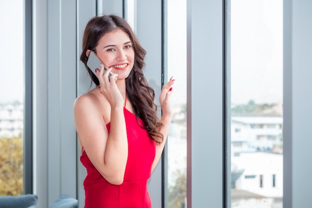 Linda mulher caucasiana, segurando o telefone na sala de estar