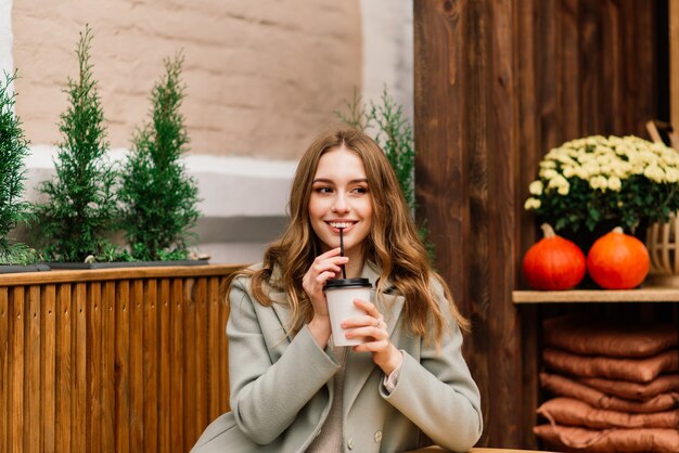 Linda mulher caucasiana tomando café em um café, sorrindo, falando ao telefone