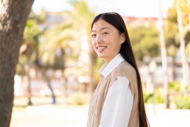 Linda mulher chinesa ao ar livre com expressão feliz