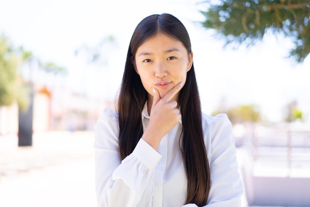 Linda mulher chinesa ao ar livre pensando