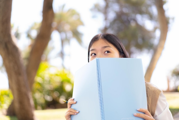 Linda mulher chinesa ao ar livre segurando um notebook