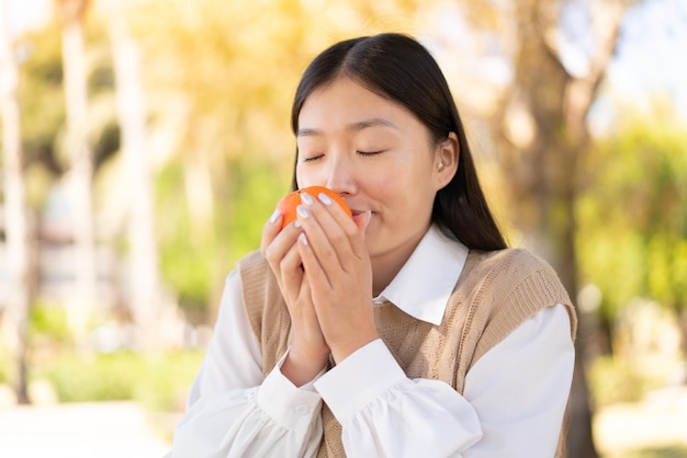 Linda mulher chinesa ao ar livre segurando uma laranja