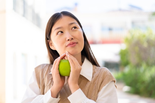 Linda mulher chinesa ao ar livre segurando uma maçã