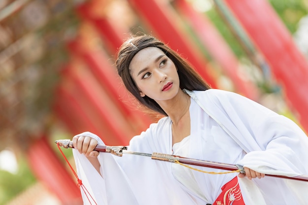 Linda mulher chinesa com um terno tradicional com uma espada afiada nas mãos dela.