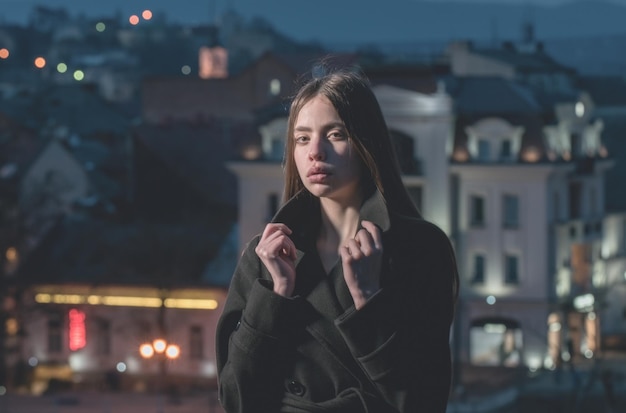 Linda mulher com casaco preto à noite na cidade