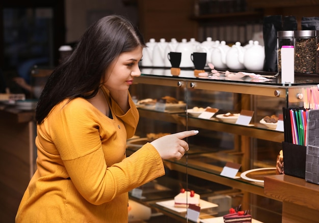 Linda mulher com excesso de peso perto de vitrine de pastelaria modelo plus size