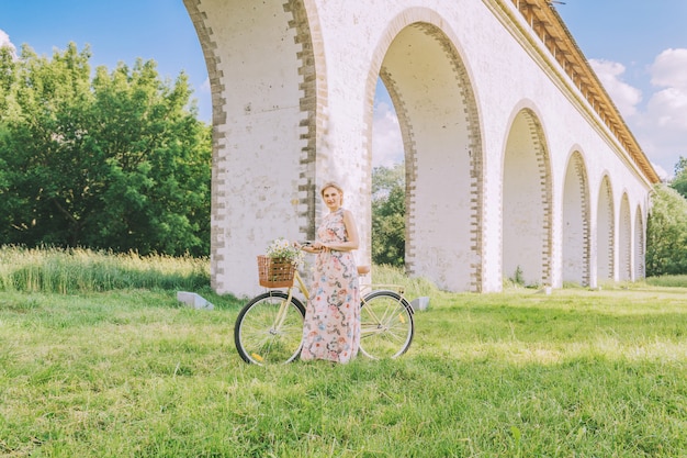 Linda mulher com sua bicicleta no fundo do aqueduto de ponte na temporada de verão