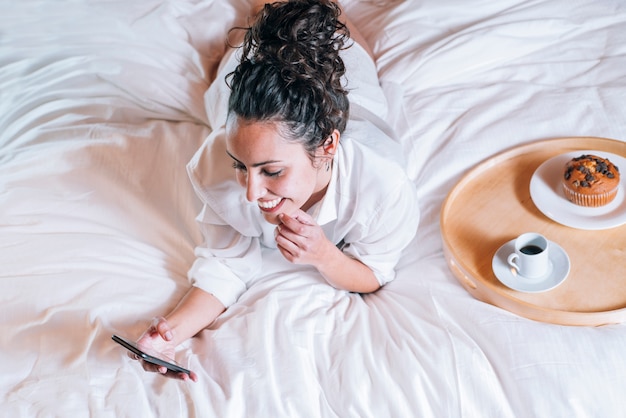 Linda mulher com telefone na cama