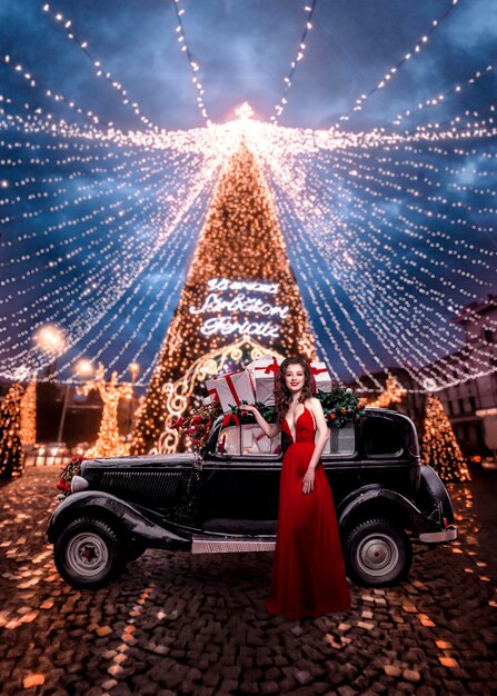 Linda mulher com um carro decorado com presentes de Natal