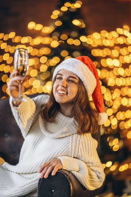 Linda mulher com um casaco quente, meias e chapéu de Natal, sentada no chão