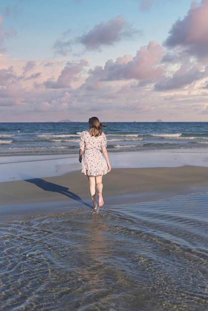 Linda mulher da Bielorrússia andando na praia contra o céu dramático e romântico