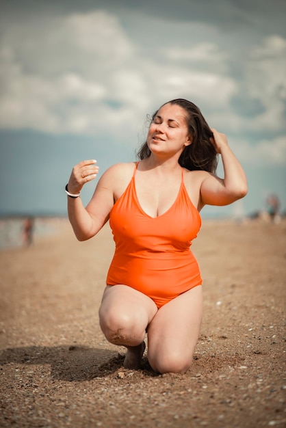 Linda mulher de 40 anos na praia em maiô plus size