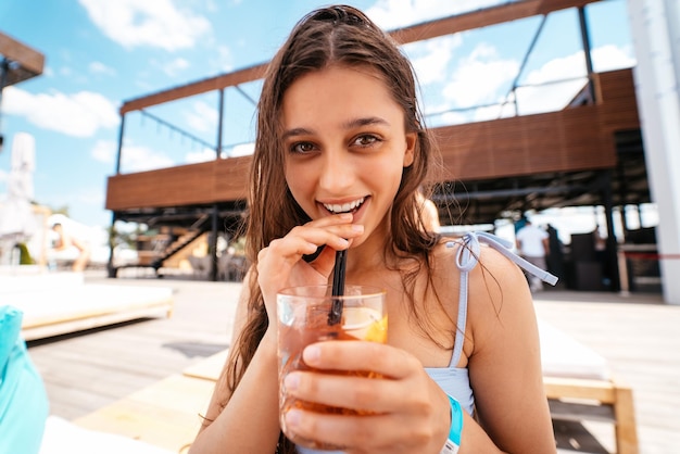 Linda mulher de biquíni bebendo coquetel na festa na piscina