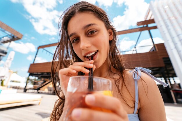 Linda mulher de biquíni bebendo coquetel na festa na piscina