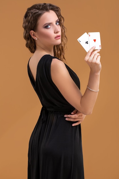 Linda mulher de cabelos castanhos segurando dois ases como um sinal de jogo de pôquer, jogos de azar e cassino