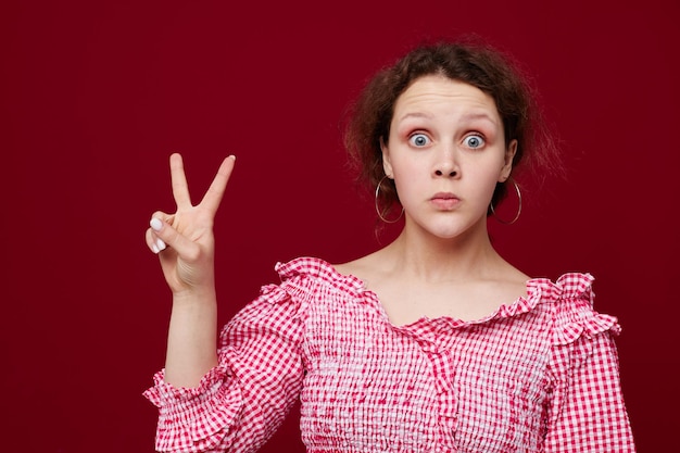 Linda mulher de camisa rosa posando emoções fundo vermelho inalterado