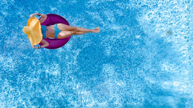 Linda mulher de chapéu na piscina aérea vista superior de cima, jovem garota de biquíni relaxa e nada no anel inflável donut e se diverte na água em férias em família, estância de férias tropical