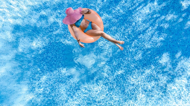 Linda mulher de chapéu na piscina vista aérea de cima de uma jovem de biquíni relaxa