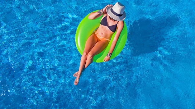 Linda mulher de chapéu na vista aérea da piscina de cima, jovem de biquíni relaxa