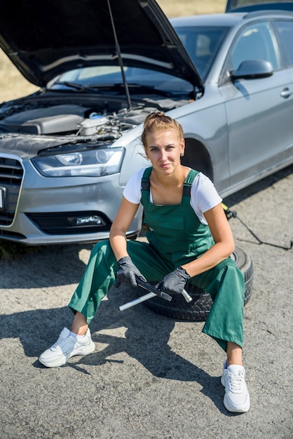 Linda mulher de macacão com as chaves consertando um carro quebrado em sua jornada