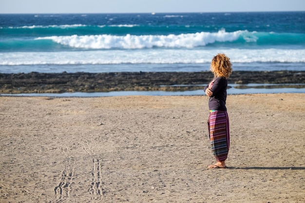 Linda mulher de meia idade caucasiana solitária anda e aproveita a praia de ninguém na liberdade da temporada e o conceito de estilo de vida alternativo para a senhora da independência sentindo o oceano e a natureza