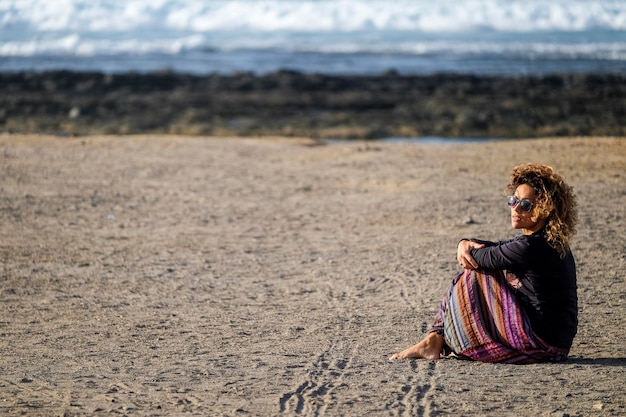 Linda mulher de meia idade caucasiana solitária anda e aproveita a praia de ninguém na liberdade da temporada e o conceito de estilo de vida alternativo para a senhora da independência sentindo o oceano e a natureza