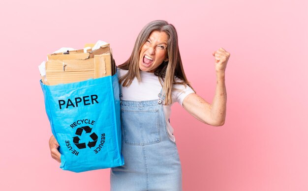 Foto linda mulher de meia-idade gritando agressivamente com uma expressão raivosa, reciclando o conceito de papelão