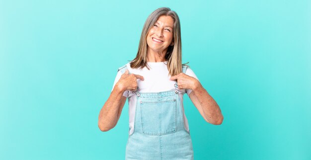 Foto linda mulher de meia-idade se sentindo feliz e apontando para si mesma com uma expressão animada