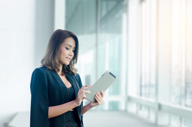 Linda mulher de negócios asiático usando tablet no escritório