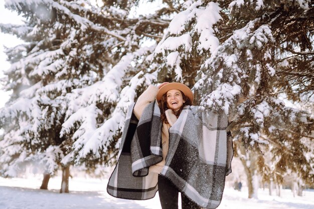 Linda mulher de pé entre árvores nevadas e aproveitando a primeira neve Feliz Natal