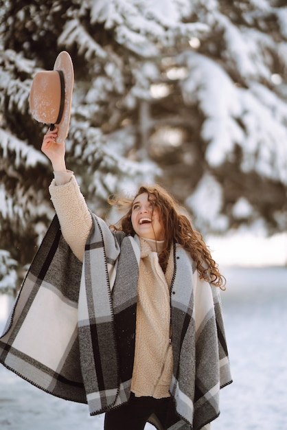 Linda mulher de pé entre árvores nevadas e aproveitando a primeira neve Feliz Natal