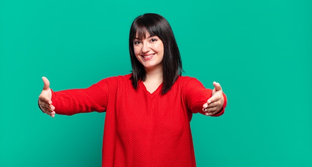 Linda mulher de tamanho grande sorrindo alegremente dando um abraço caloroso, amigável e afetuoso de boas-vindas, sentindo-se feliz e adorável