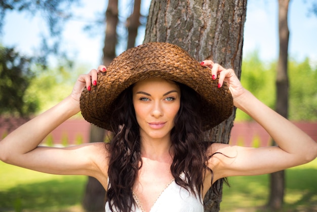 Linda mulher de vestido branco de verão e chapéu de palha no jardim