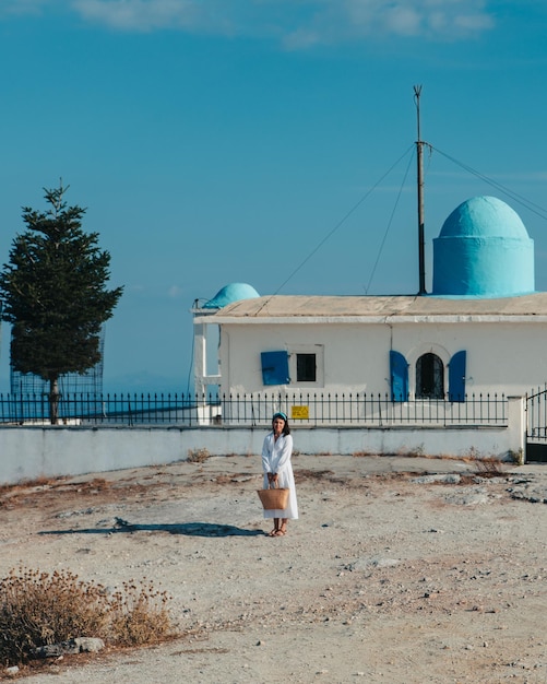 Linda mulher de vestido branco perto da antiga igreja da grécia