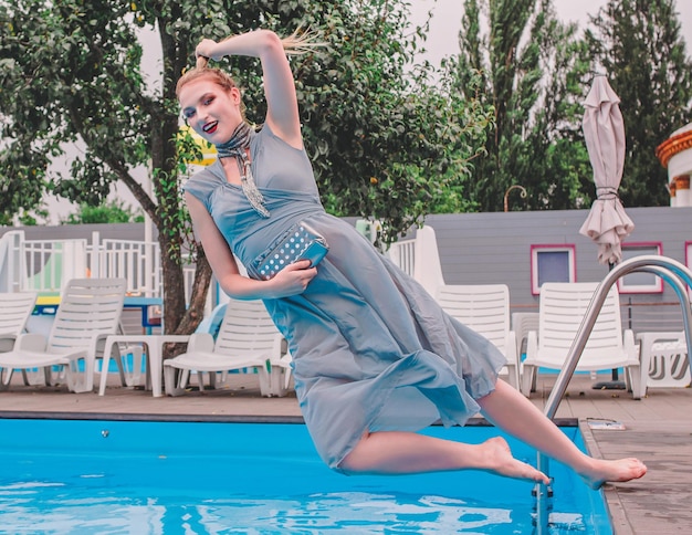 linda mulher de vestido cinza pulando na piscina