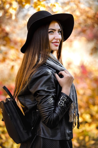 Linda mulher de vestido preto e chapéu no outono