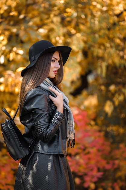 Linda mulher de vestido preto e chapéu no outono