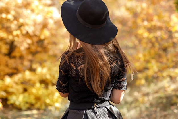 Linda mulher de vestido preto e chapéu no outono