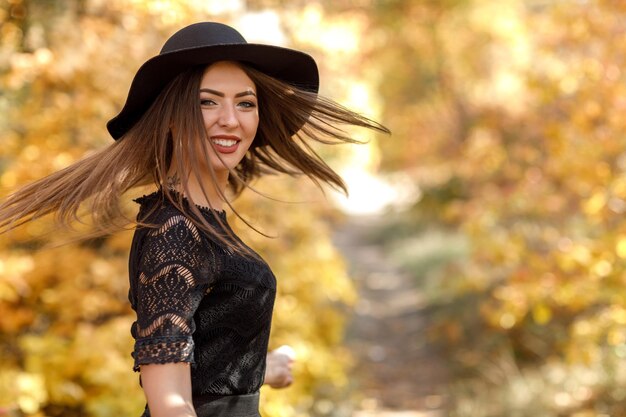 Linda mulher de vestido preto e chapéu no outono