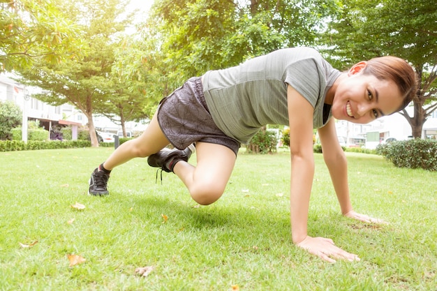 Linda mulher desportiva está fazendo exercícios no parque verde