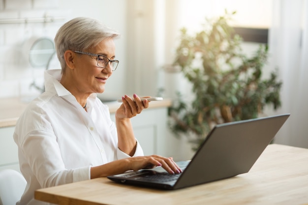 linda mulher elegante com um telefone celular em uma mesa com um laptop