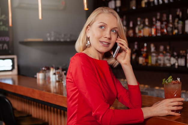 Linda mulher elegante usando telefone inteligente na boate, copie o espaço. Mulher atraente chamando alguém usando seu celular no bar