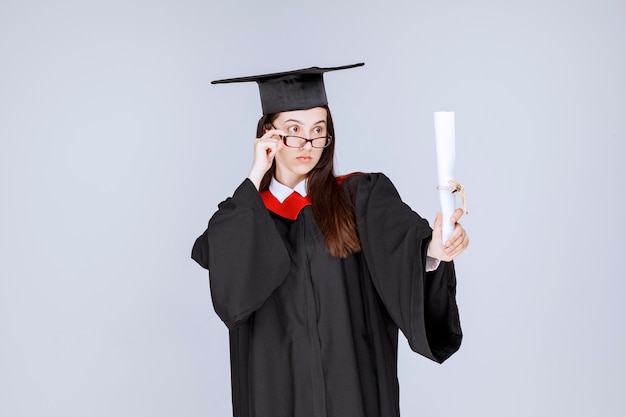 Linda mulher em um vestido com diploma de graduação na faculdade. Foto de alta qualidade