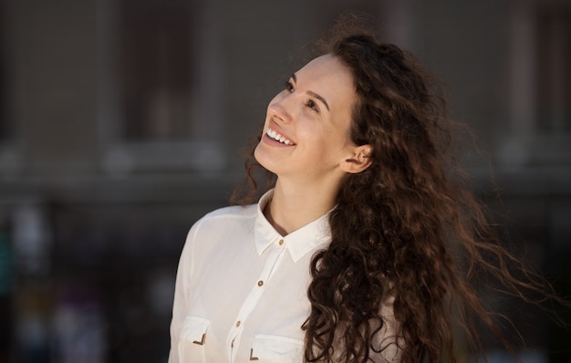 Linda mulher encaracolada morena sorrindo ao ar livre