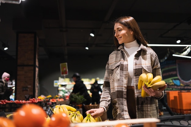 Linda mulher escolhe bananas no supermercado