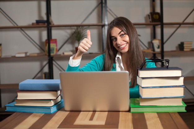 Foto linda mulher está feliz com seu trabalho bem sucedido com laptop na mesa de madeira