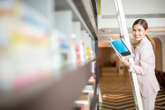 Linda mulher está lendo livros na biblioteca